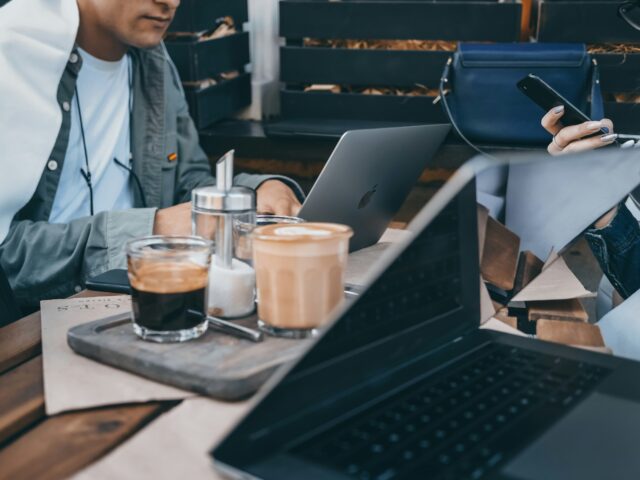 Deux personnes à une table avec des portables et des cafés.