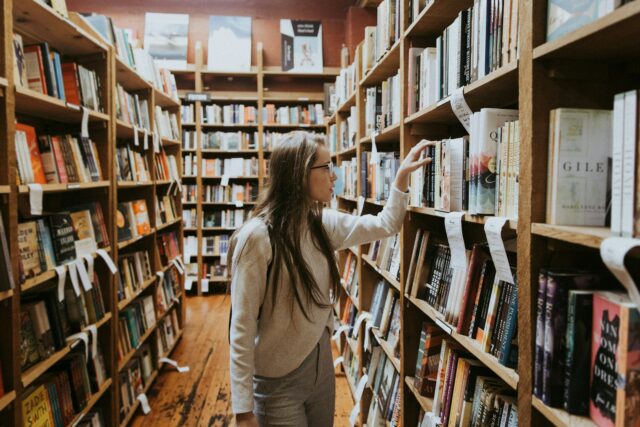 Une femme qui regarde des livres dans une bibliothèque.