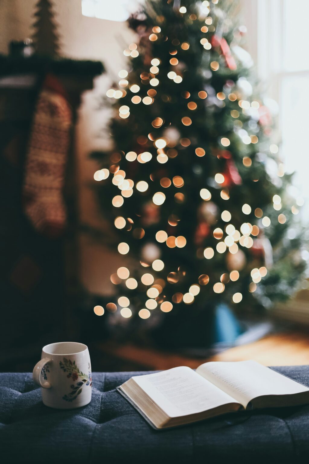 Une tasse de café et une Bible devant un sapin de Noël.