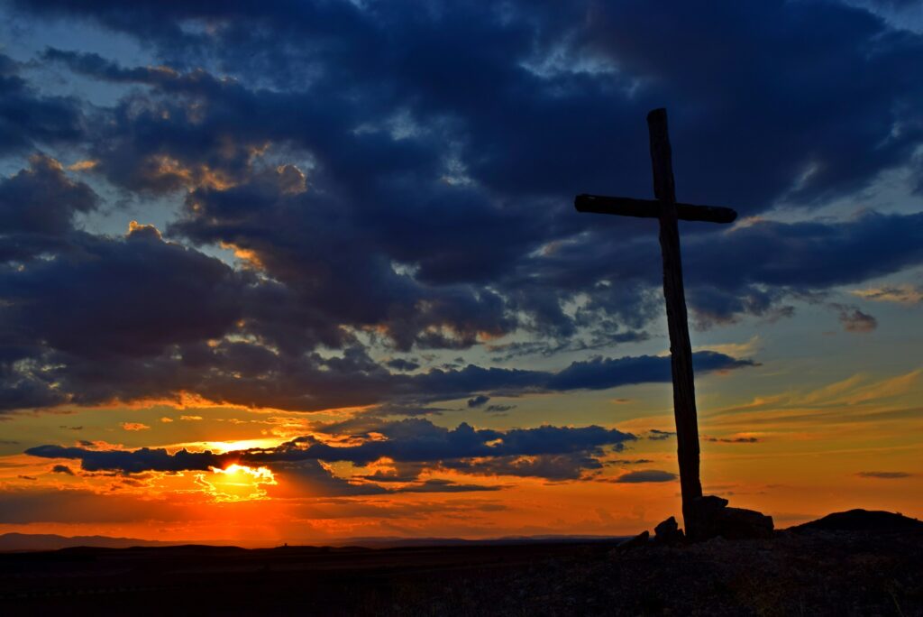 Un coucher de soleil derrière une croix.