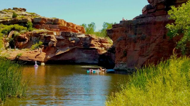 Des gens qui nagent dans l'eau entourée de rochers.