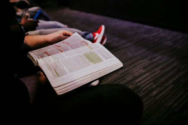 Un homme assis, tenant sa Bible ouverte.