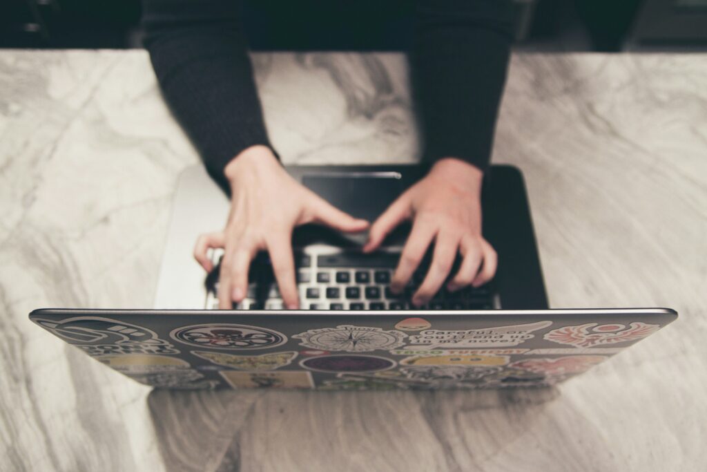 Des mains tapant sur un ordinateur portable.