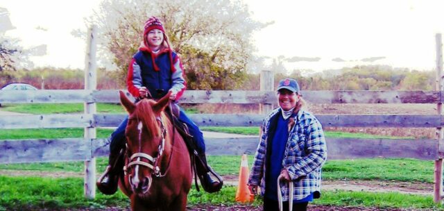 Une femme aidant une jeune fille à monter à cheval.