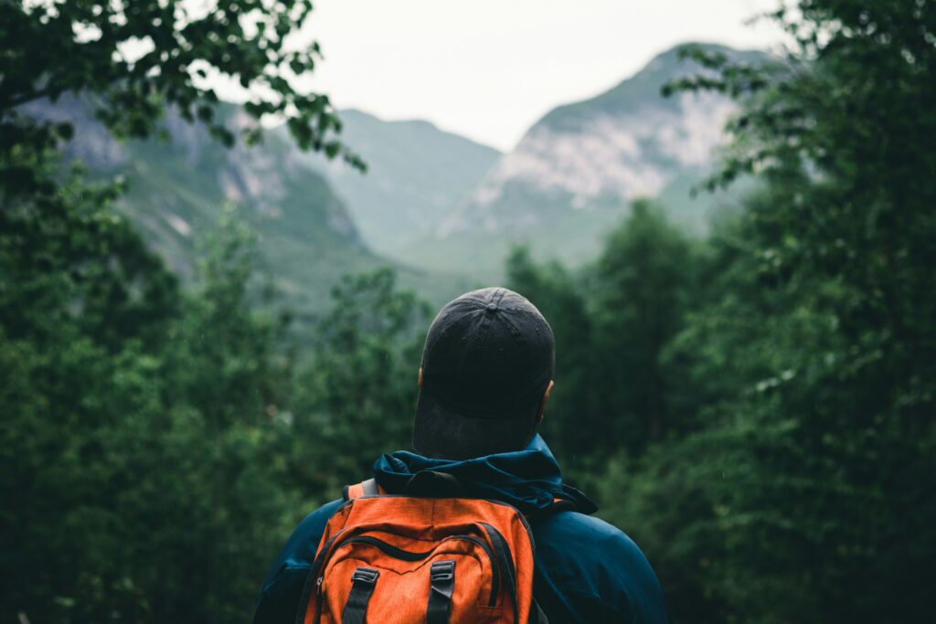 Un homme marchant dans la forêt avec des montagnes. Foi intentionnelle en été.