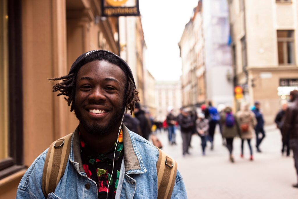 Un homme souriant portant un sac à dos dans la ville.