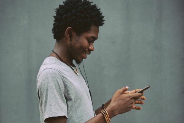 Jeune homme qui sourit en regardant son téléphone.