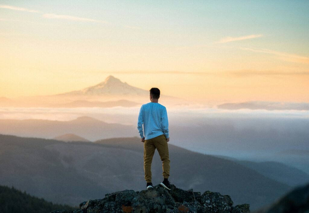 Un homme debout sur une montagne, regardant la vue.