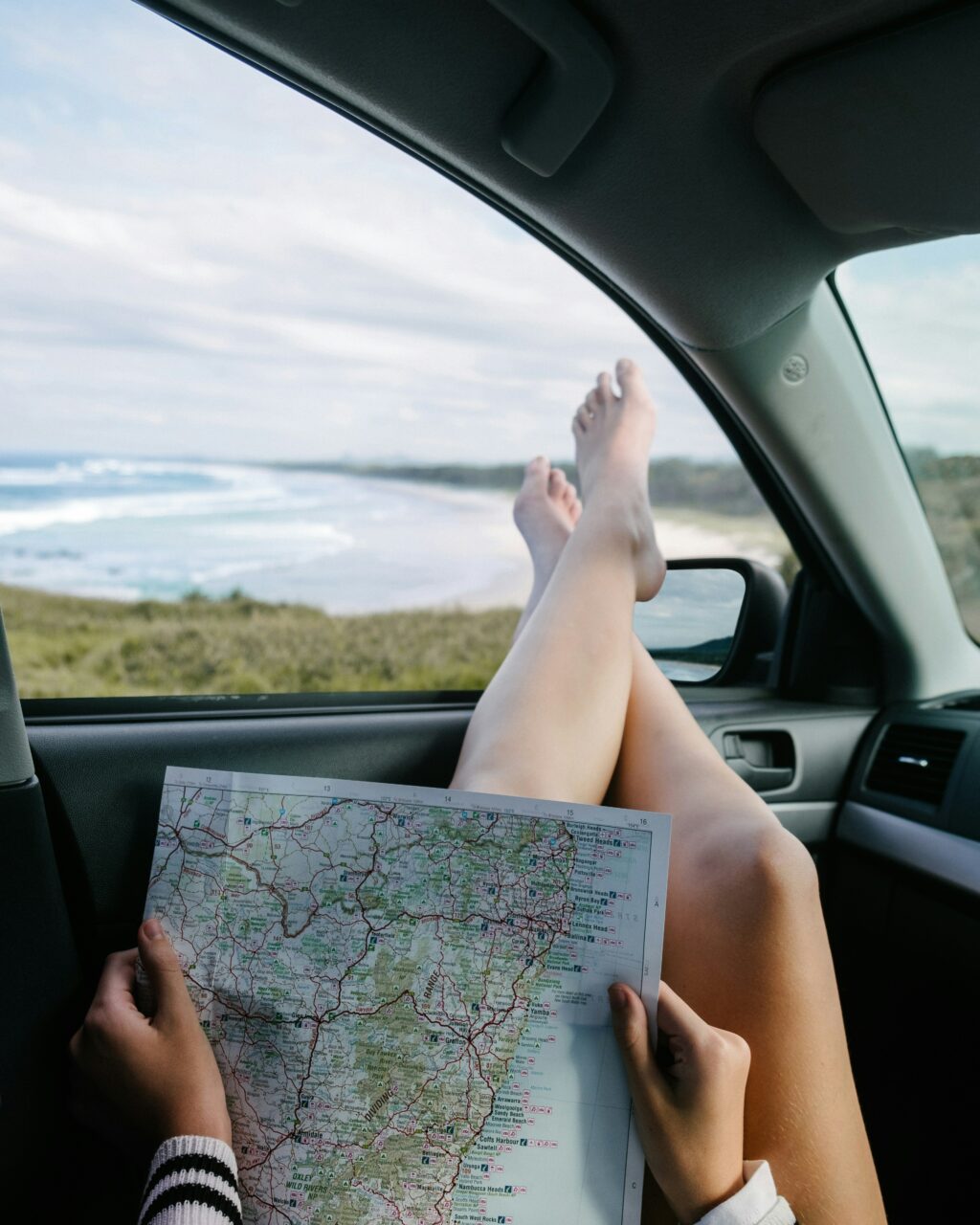 Une femme assise dans une voiture avec une carte, les pieds sortis par la fenêtre. Foi intentionnelle en été.