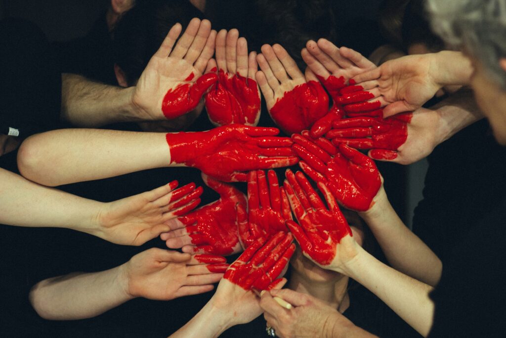 Un groupe de mains ensemble avec un cœur rouge peint sur chacune d'elles.
