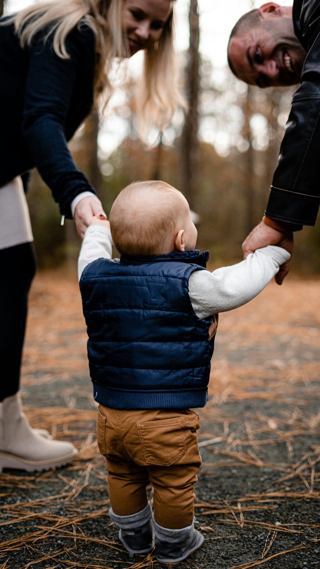 Un enfant qui marche avec ses parents, tenant leurs mains et les regardant.