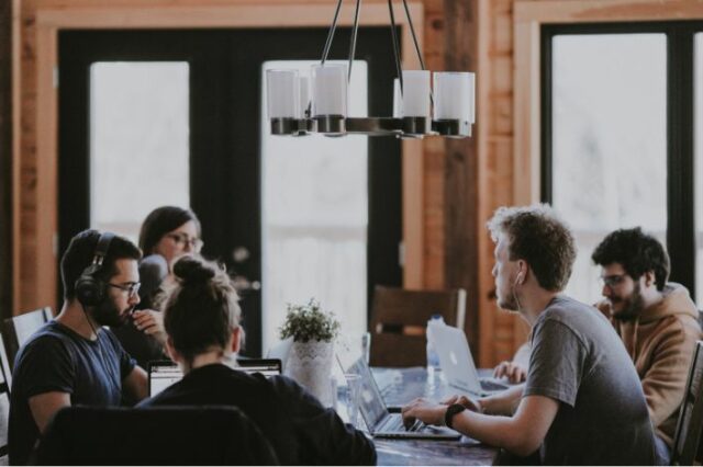 Des personnes travaillant sur leurs ordinateurs portables autour d’une table.