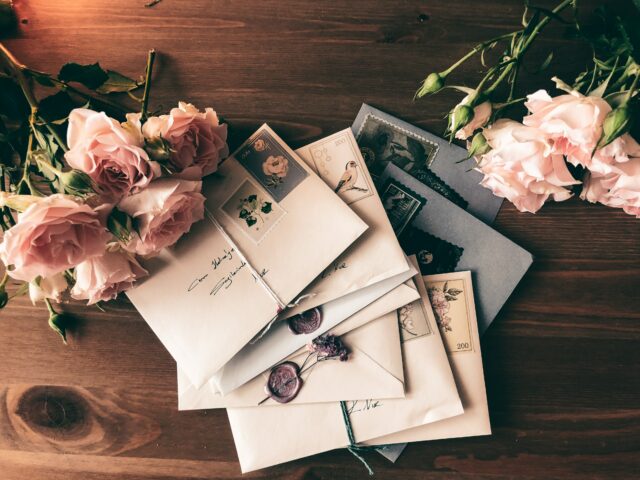 Une pile de lettres et de roses sur une table.
