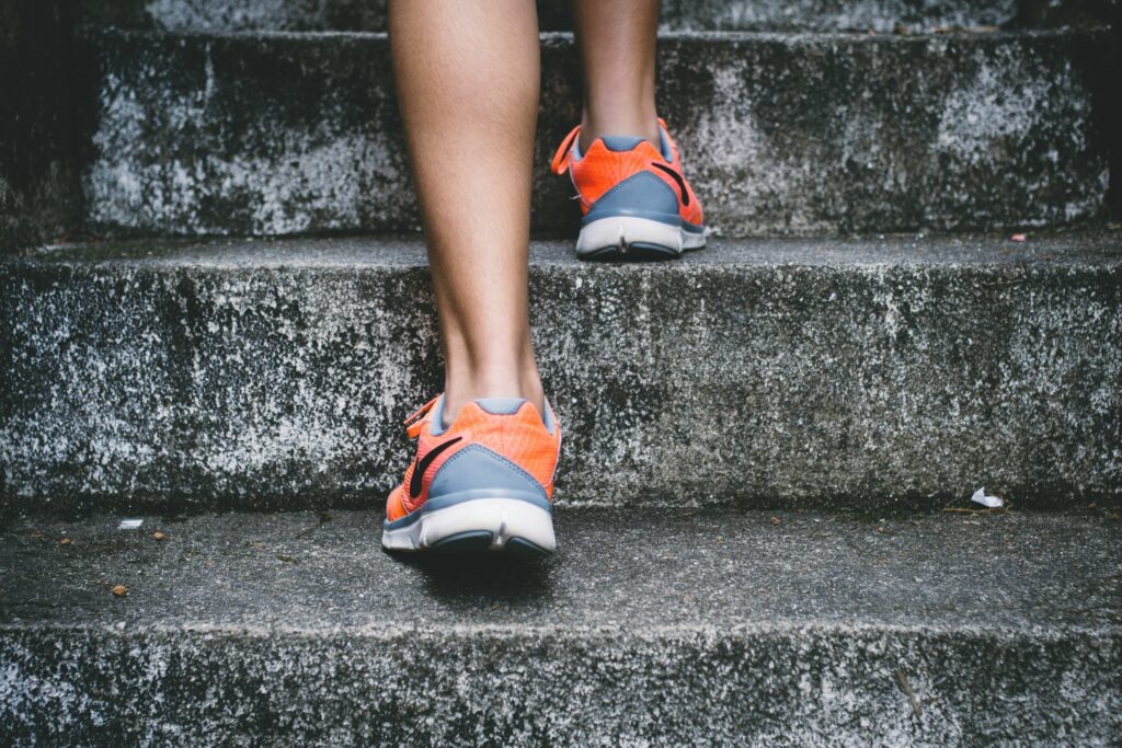 Les jambes d'une personne portant des chaussures de course, montant des escaliers extérieurs.