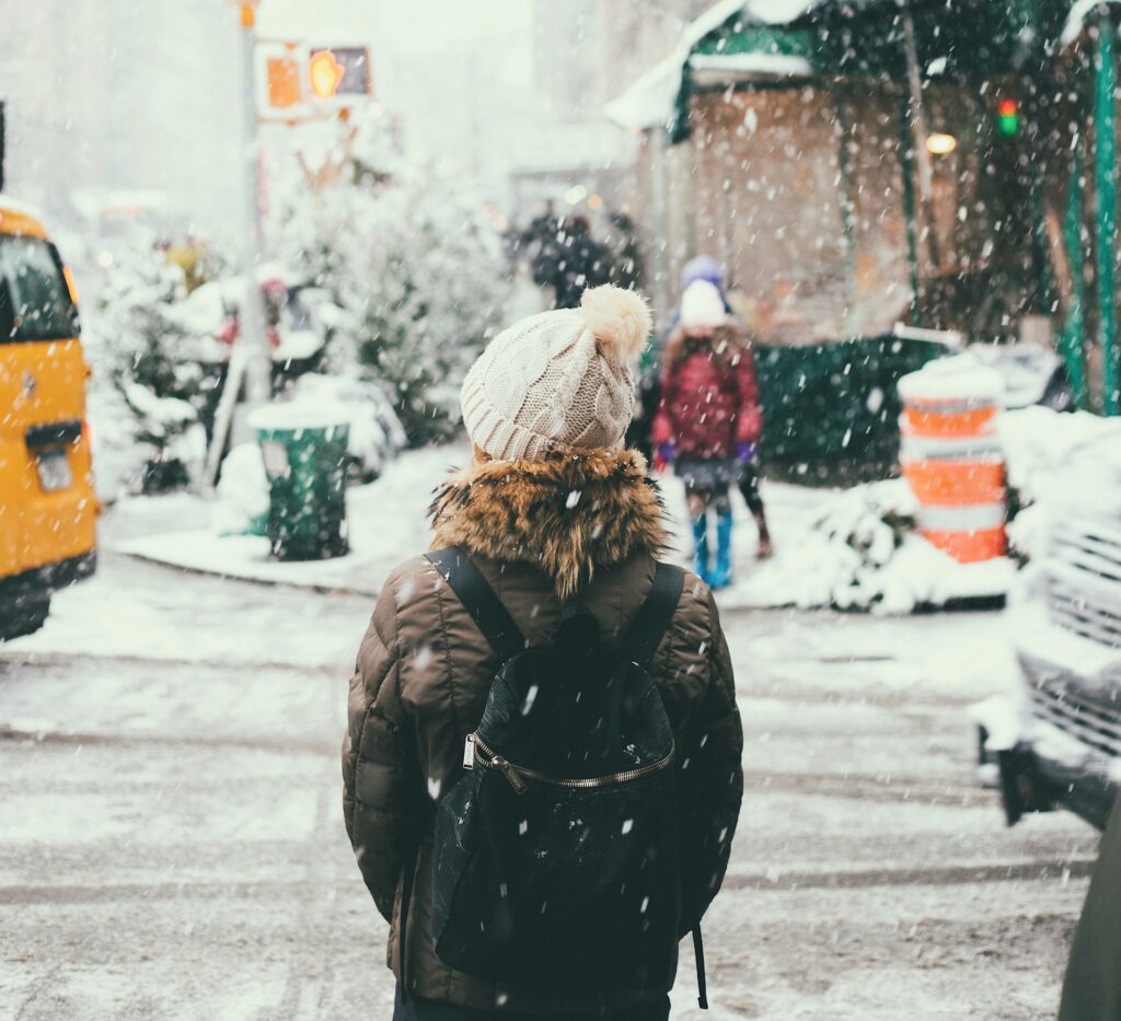Un étudiant attendant de traverser la rue pendant qu'il neige.