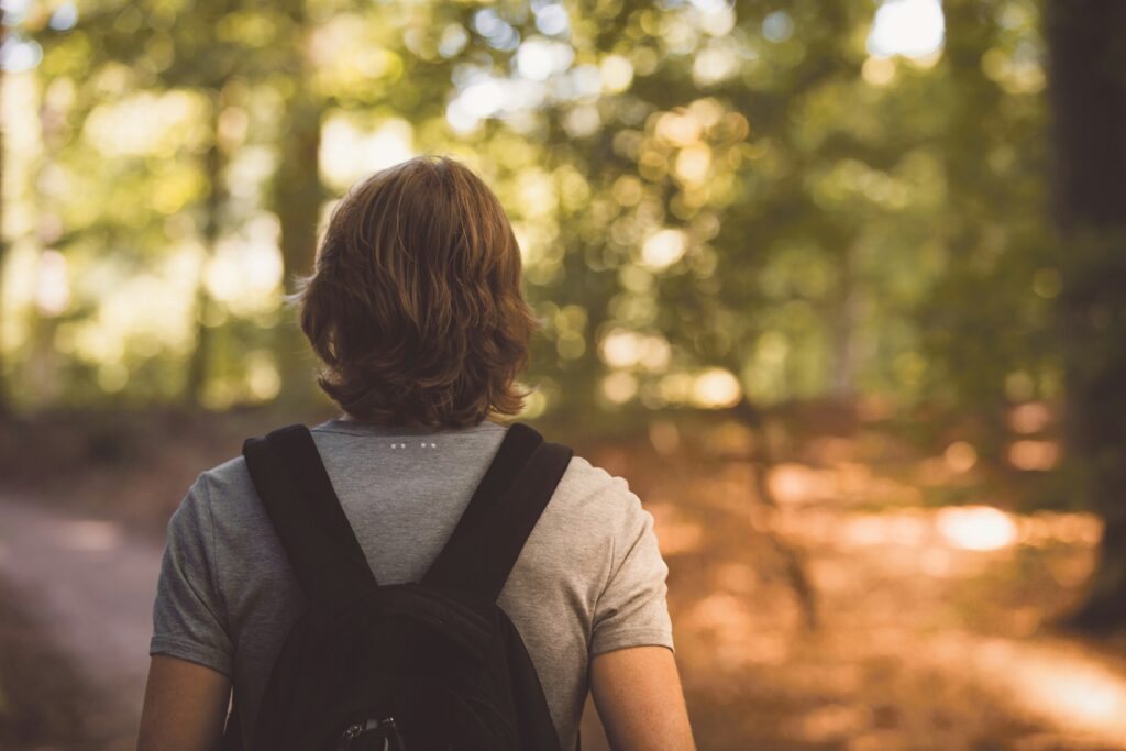 Un jeune homme avec un sac à dos dans les bois.