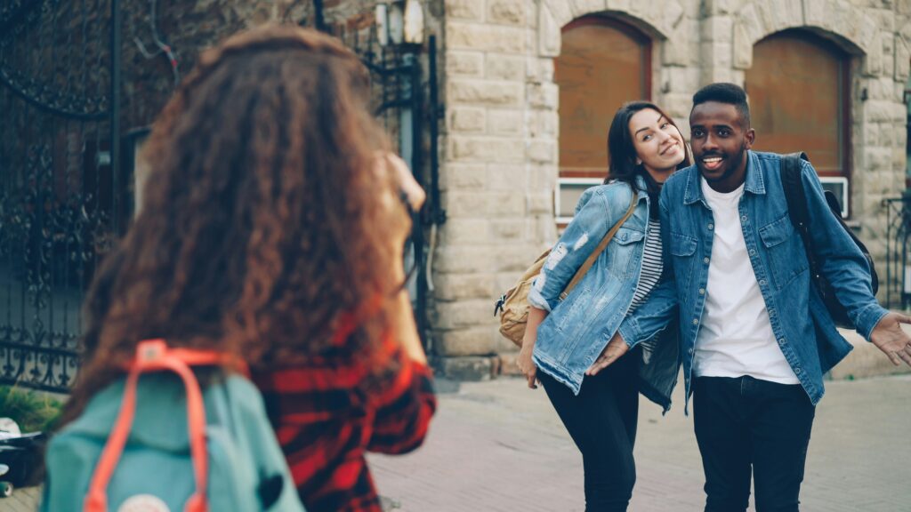 Une femme prend une photo d’une femme et d’un homme sur le campus universitaire.