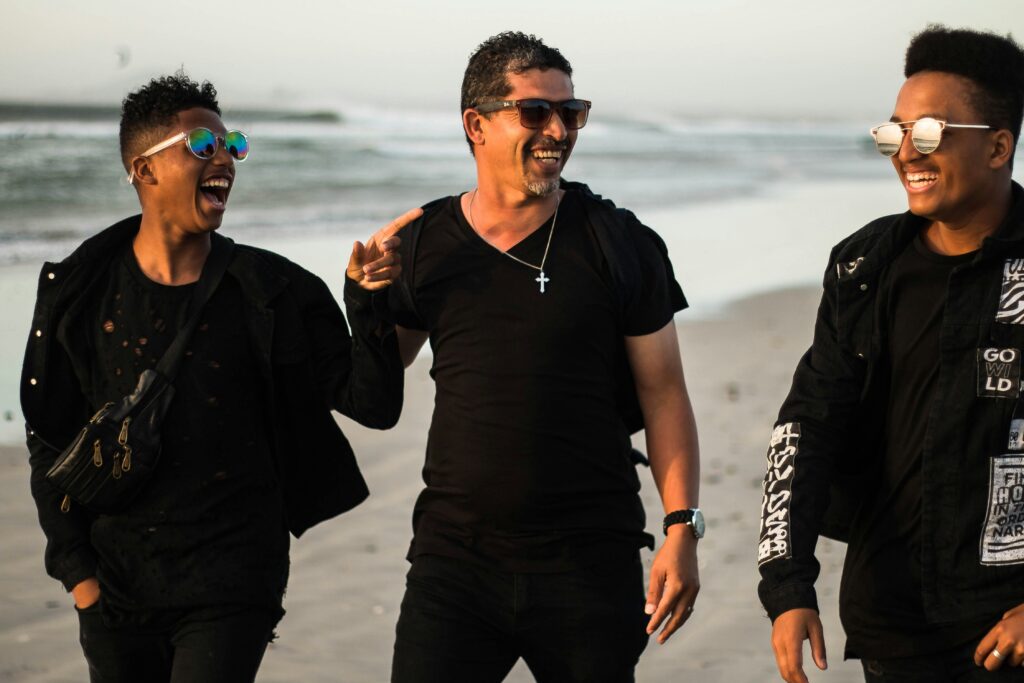 Trois hommes marchant sur la plage en riant.