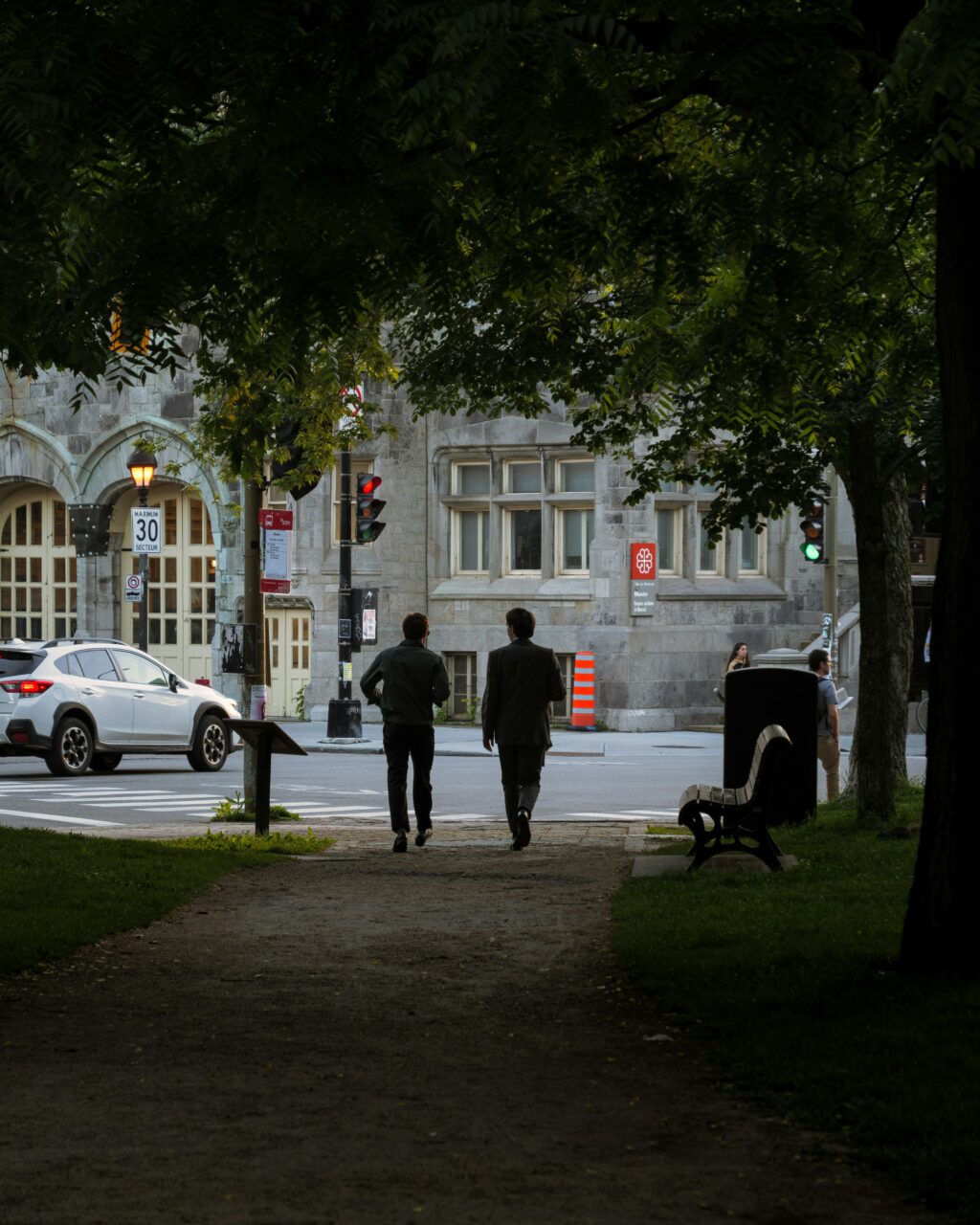 Deux hommes marchant à travers les arbres en ville.