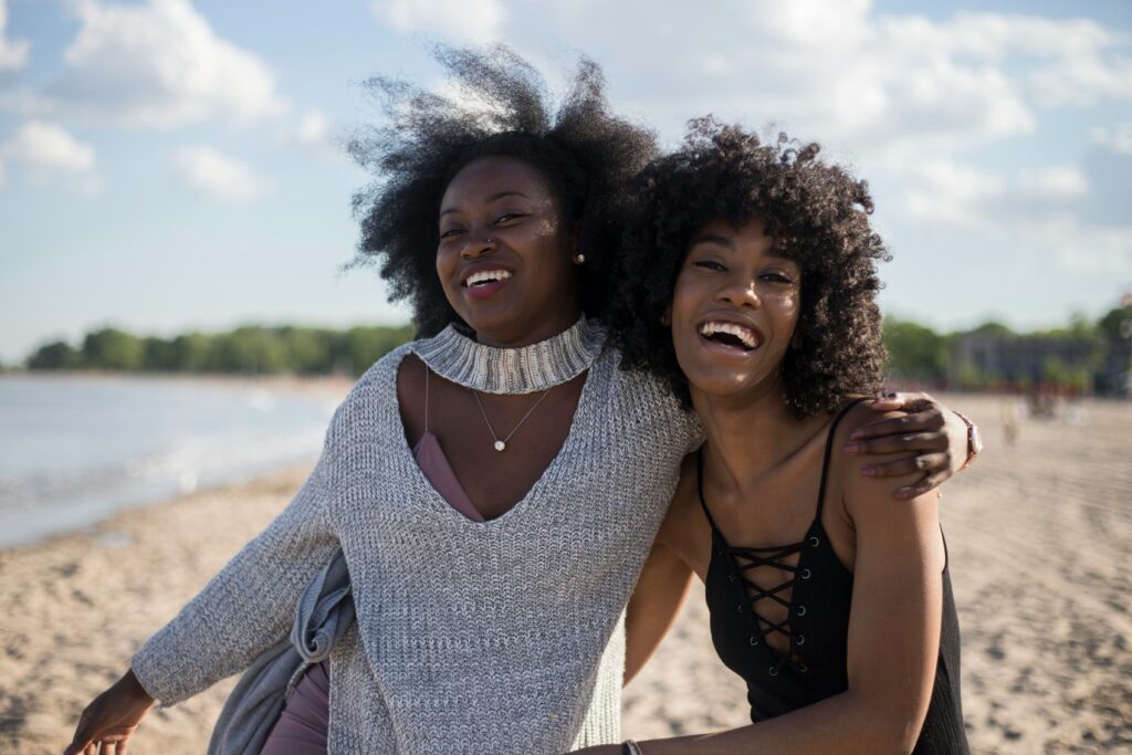 Deux femmes riant ensemble à la plage.