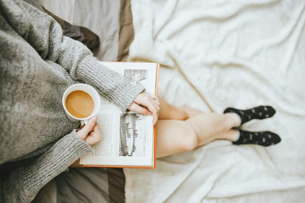 Une femme assise avec un livre et un café.