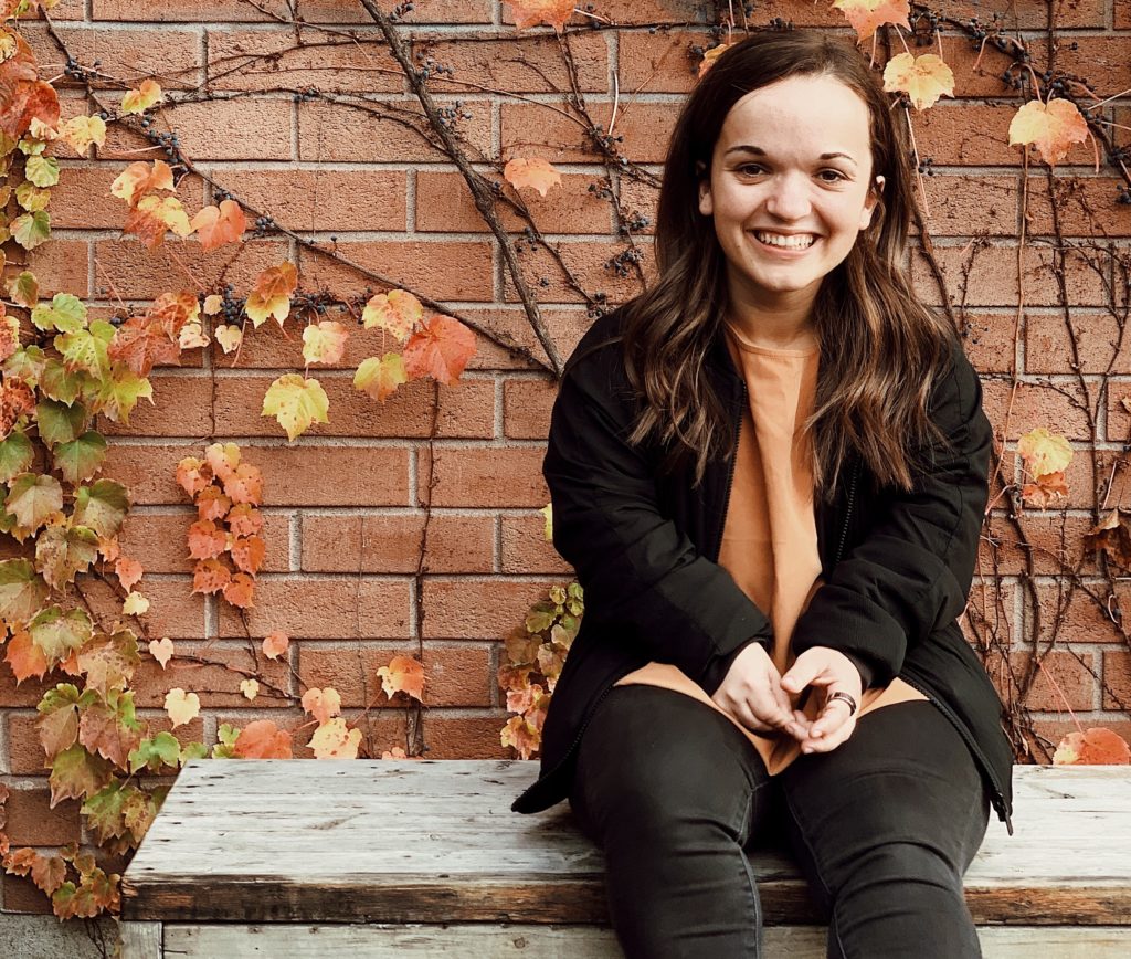 Une femme souriante assise sur un banc.