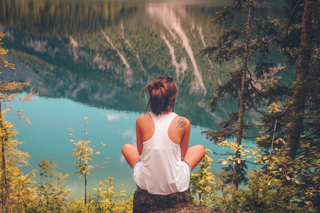 Une jeune femme assise sur un rocher regardant l'eau.
